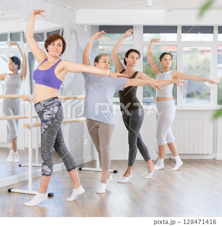 Woman practicing ballet moves during amateur group class 128471416
