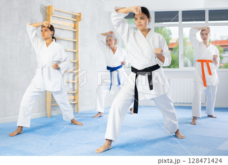 Female martial arts instructor leading karate kata training for group Female martial arts instructor leading karate kata training for group 128471424