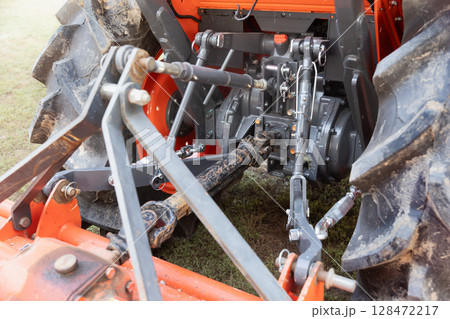 Rear end of farm tractor showing the PTO shaft and three point hitch  is used to connect agricultural implements. 128472217