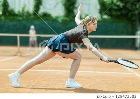 Girl plays tennis on open court with opponent Girl plays tennis on open court with opponent 128472382