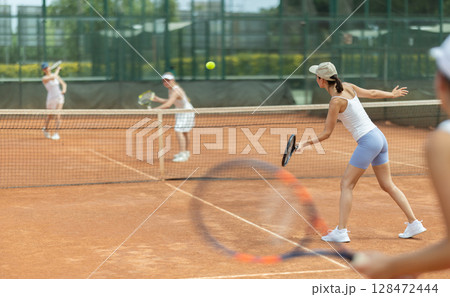 Woman playing tennis against female opponent on tennis court Woman playing tennis against female opponent on tennis court 128472444