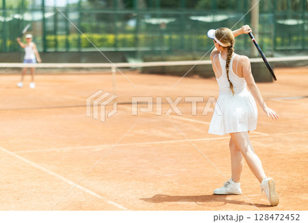 Female athlete plays tennis on open court 128472452