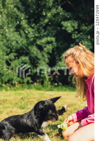 Young woman playing with her dog and shuttlecocks concept. Summer outdoor activities. Staycation leisure time. Petrenthood pet love Young woman playing with her dog and shuttlecocks concept. Summer outdoor activities. Staycation leisure time. Petrenthood pet love 128472699