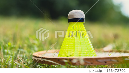 Badminton racket and shuttlecock lie on green grass. Outside recreation and fresh air. Healthy lifestyle nature connection sport summer activities. Stress relief hobby Badminton racket and shuttlecock lie on green grass. Outside recreation and fresh air. Healthy lifestyle nature connection sport summer activities. Stress relief hobby 128472702