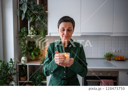 Calm woman smell candle fragrance, enjoying peaceful rest at home. Meditation relaxation, wellness 128473750