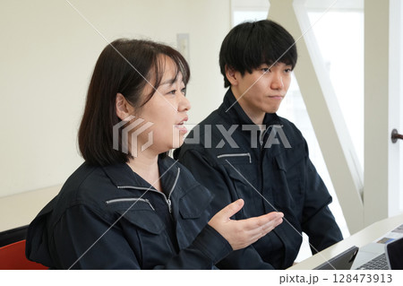 作業着姿で後輩を指導する先輩エンジニア 作業着姿で後輩を指導する先輩エンジニア 128473913