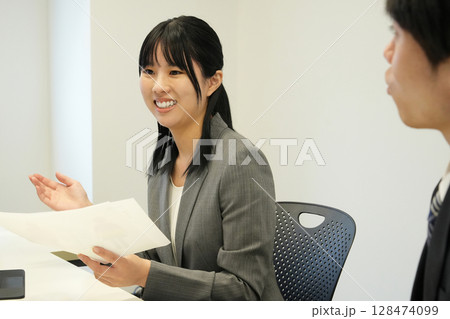 会議室で資料を手にプレゼンを行う上司の女性 128474099