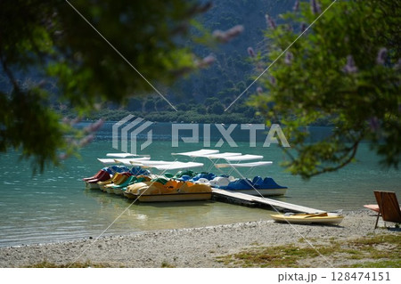 Colorful Pedal Boats Docked at Scenic Lake Shore Colorful Pedal Boats Docked at Scenic Lake Shore 128474151
