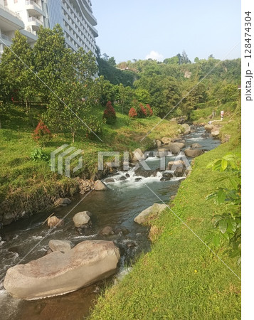 scenic river flowing through a lush green landscape with rock and trees scenic river flowing through a lush green landscape with rock and trees 128474304
