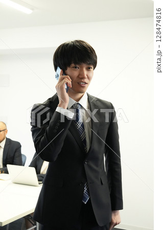 会社の電話で話をするビジネスマン 会社の電話で話をするビジネスマン 128474816