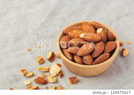 Roasted almonds in wooden bowl on linen table cloth background 128475627