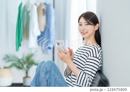 部屋でスマホを使っている若い女性。 部屋でスマホを使っている若い女性。 128475809