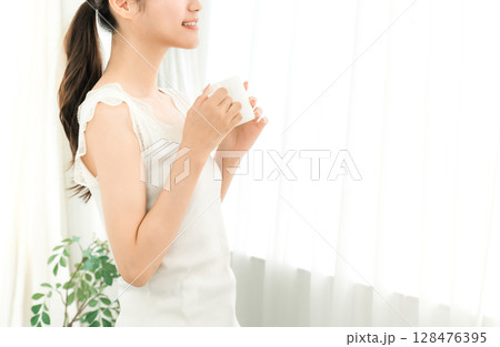 朝、家で白湯・コーヒー・ホットドリンク・カフェオレ・カフェラテを飲む笑顔のアジア人女性 朝、家で白湯・コーヒー・ホットドリンク・カフェオレ・カフェラテを飲む笑顔のアジア人女性 128476395
