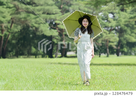 日傘をさして散歩する若い女性 128476479
