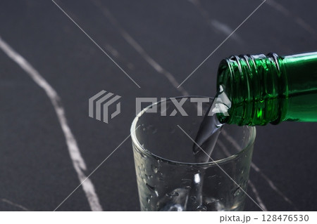 韓国の伝統的な蒸留酒、よく冷えた韓国焼酎（ソジュ）をグラスに注ぐ 128476530