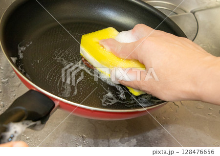 洗剤を含んだスポンジでフライパンを洗う 128476656