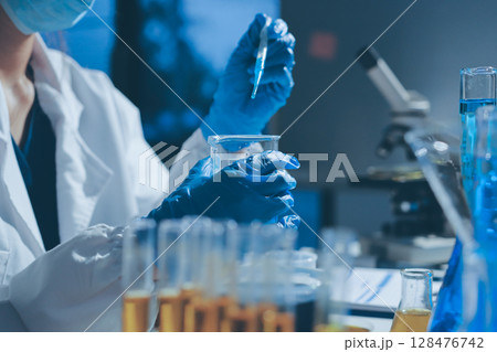Scientist pipetting medical samples into microplate in laboratory 128476742