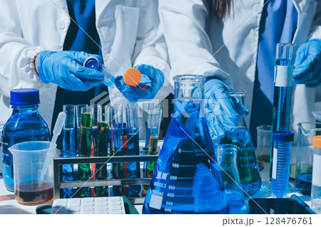 Scientist pipetting medical samples into microplate in laboratory 128476761