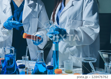 Scientist pipetting medical samples into microplate in laboratory 128476762