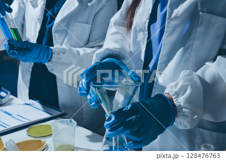 Scientist pipetting medical samples into microplate in laboratory 128476763