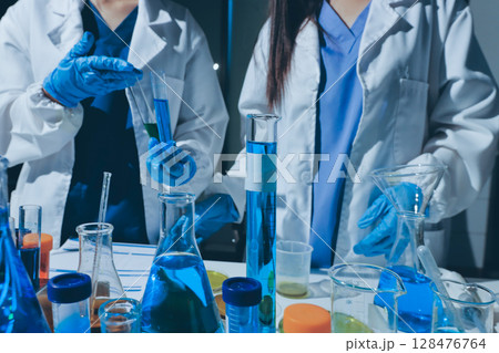 Scientist pipetting medical samples into microplate in laboratory 128476764