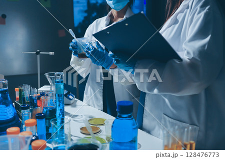 Scientist pipetting medical samples into microplate in laboratory 128476773