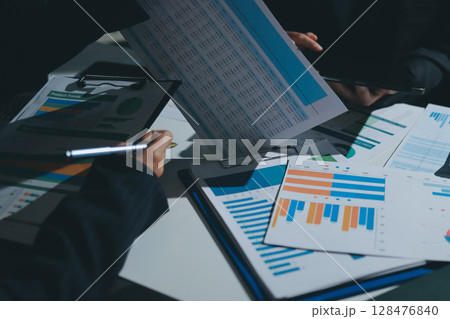 Group of business women working on a financial data expenses document. Group of business women working on a financial data expenses document. 128476840