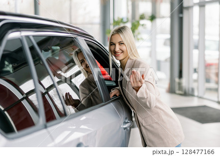 Saleswoman inviting to enter new car in dealership 128477166