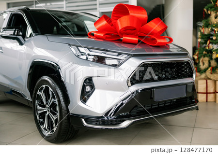Silver scar with red bow parked in dealership showroom 128477170