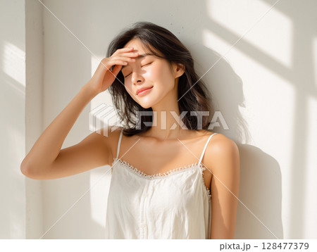 透明感あふれる白いキャミソール姿の女性モデル 128477379