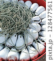 Fishing Buoys and Rope Close-up of a red tub filled with white buoys and tangled rope. 128477561