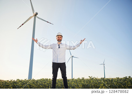 Conception of success and freedom. Service engineer is on the field with windmills Conception of success and freedom. Service engineer is on the field with windmills 128478082