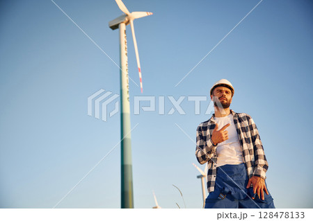 Pointing to one of the turbines. Service engineer is on the field with windmills Pointing to one of the turbines. Service engineer is on the field with windmills 128478133