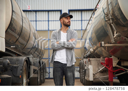 Between two vehicles. Young truck driver in casual clothes Between two vehicles. Young truck driver in casual clothes 128478738