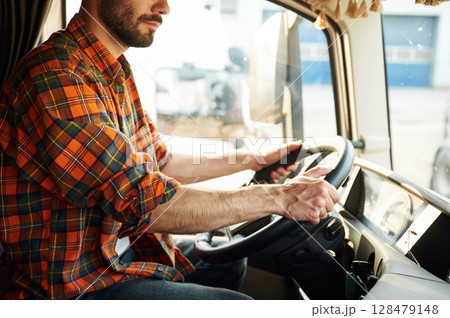Side view, sitting inside the vehicle. Young truck driver in casual clothes 128479148