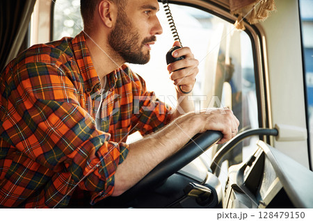 Side view, sitting inside the vehicle. Young truck driver in casual clothes 128479150