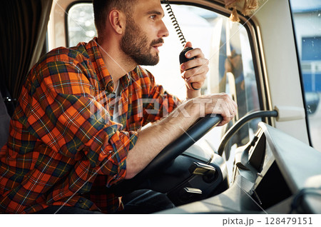 Side view, sitting inside the vehicle. Young truck driver in casual clothes 128479151
