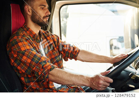 Side view, sitting inside the vehicle. Young truck driver in casual clothes 128479152