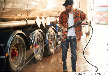 Walking and washing the vehicle. Young truck driver in casual clothes Walking and washing the vehicle. Young truck driver in casual clothes 128479203