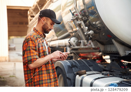 Holding smartphone. Young truck driver in casual clothes 128479209