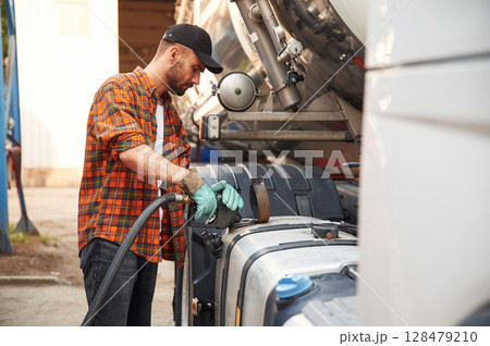 Holding refueling device. Young truck driver in casual clothes 128479210