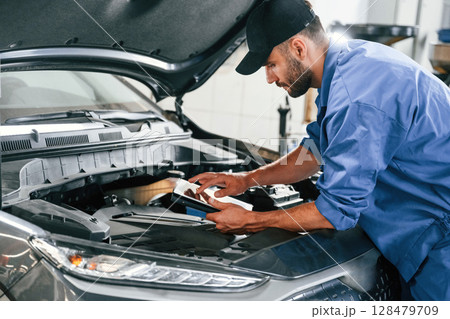 Using tablet. Auto mechanic working in garage. Repair service 128479709