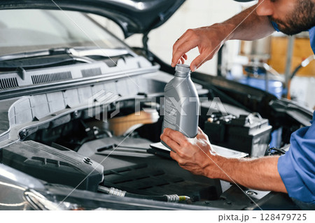 With fuel can. Auto mechanic working in garage. Repair service 128479725
