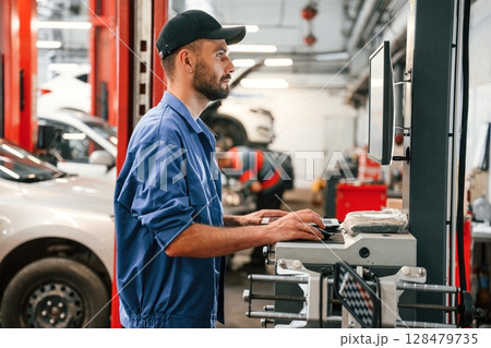 Standing by computer terminal. Auto mechanic working in garage. Repair service Standing by computer terminal. Auto mechanic working in garage. Repair service 128479735