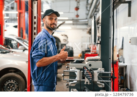 Standing by computer terminal. Auto mechanic working in garage. Repair service 128479736