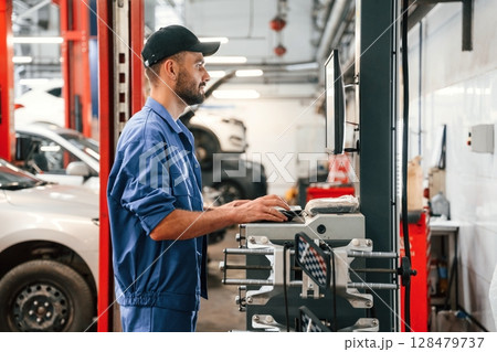 Standing by computer terminal. Auto mechanic working in garage. Repair service Standing by computer terminal. Auto mechanic working in garage. Repair service 128479737