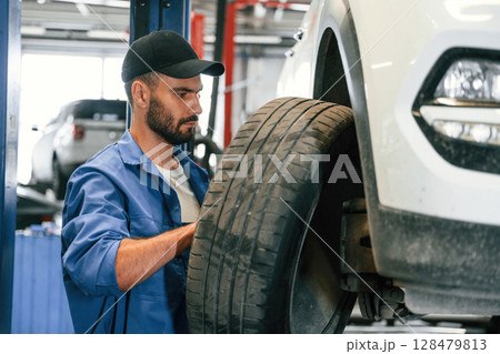 Setting up new wheel. Auto mechanic working in garage. Repair service Setting up new wheel. Auto mechanic working in garage. Repair service 128479813
