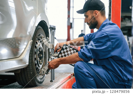 Taking care of wheel disk. Auto mechanic working in garage. Repair service 128479856