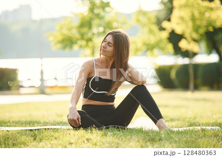In black sportive clothes. Beautiful young woman is in the park at sunny daytime In black sportive clothes. Beautiful young woman is in the park at sunny daytime 128480363