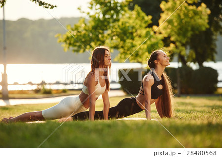Conception of sport. Two women are doing exercises outdoors on the field 128480568